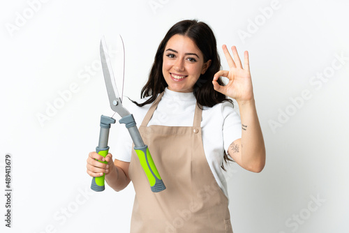 Young caucasian woman holding a plant isolated on white background showing ok sign with fingers