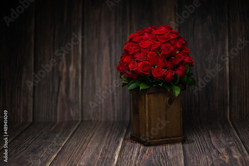 beautiful romantic photo of a bouquet of red roses with green leaves in a wooden pot, on a wooden background, with a dramatic light, a surprise for lovers, a surprise for Valentine's Day, a gift, love