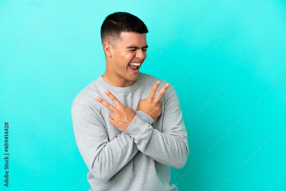 Young handsome man over isolated blue background smiling and showing victory sign Young handsome man over isolated blue background smiling and showing victory sign
