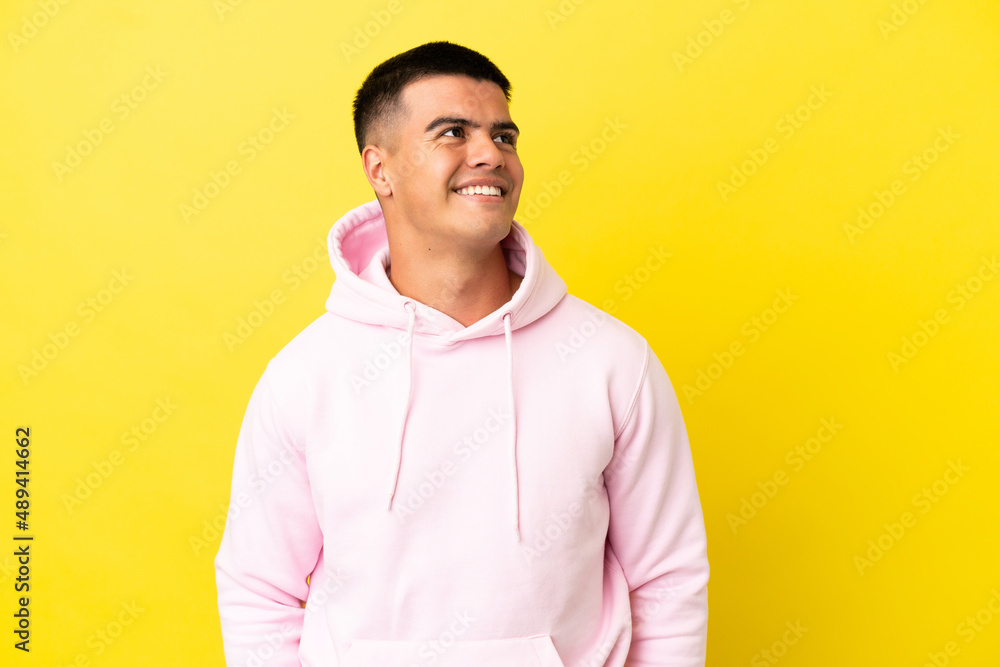 Young handsome man over isolated yellow background thinking an idea while looking up Young handsome man over isolated yellow background thinking an idea while looking up