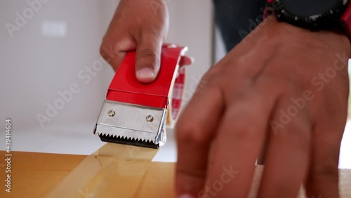 Slow motion shot, Front view hand of man use glue tape to close cardboard box, sealing big box for moving, new house concept, Selective focus