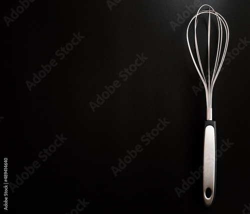Kitchen whisk for whipping on a black background. space for text