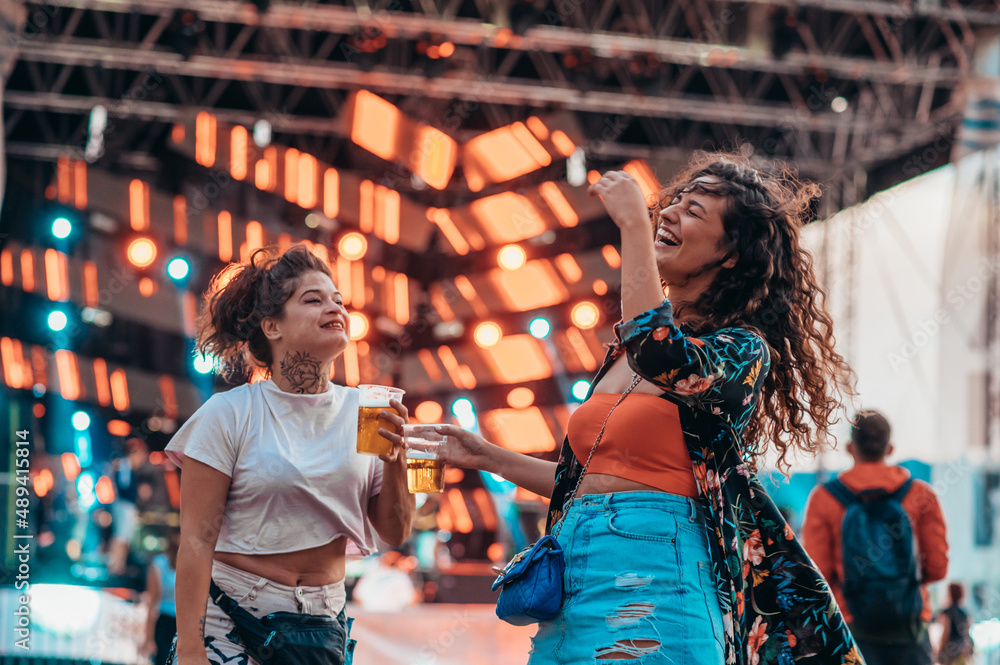 Obraz premium Two beautiful friends drinking beer and having fun on a music festival
