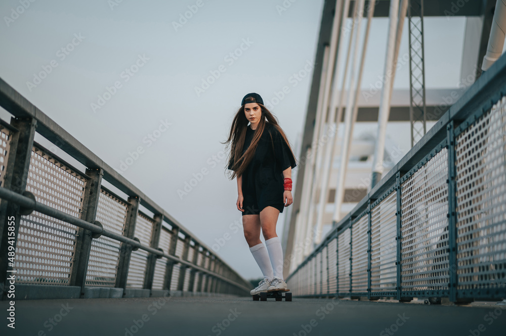 Young woman riding her longboard on the bridge