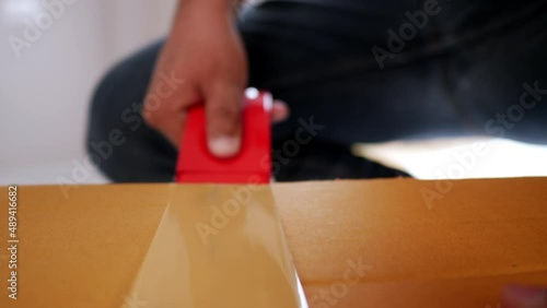 Slow motion shot, Front view hand of man use glue tape to close cardboard box, sealing big box for moving, new house concept, Selective focus