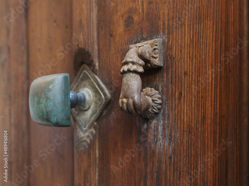Wooden door, handle and door knocker in the shape of a woman's hand.