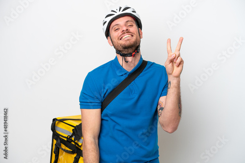 Young brazilian man with thermal backpack isolated on white background smiling and showing victory sign