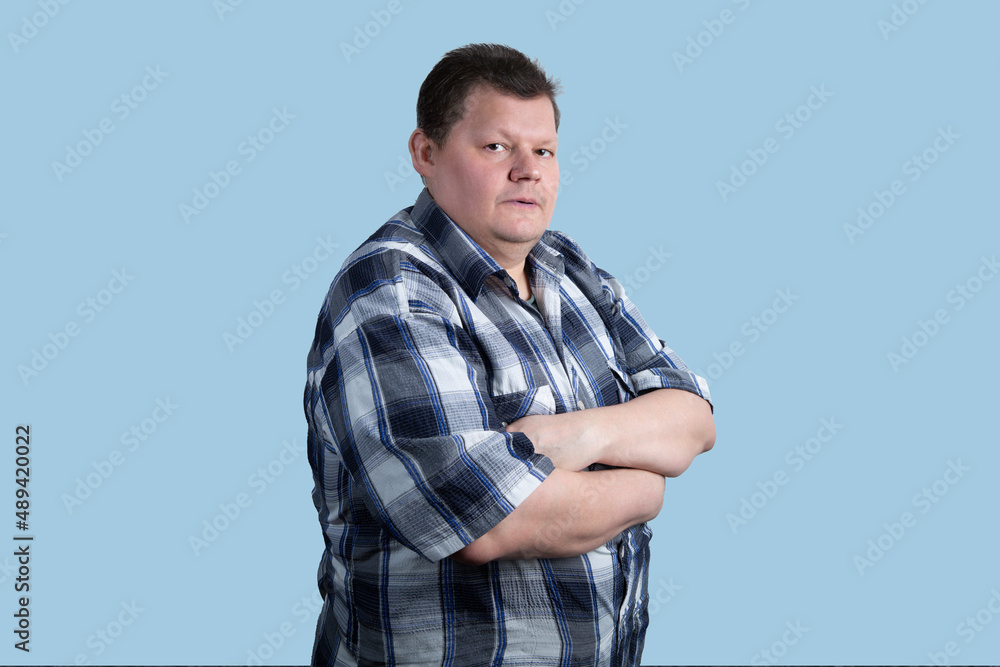 Portrait of a fat man in a shirt on a blue background. Portrait of a fat man in a shirt on a blue background.