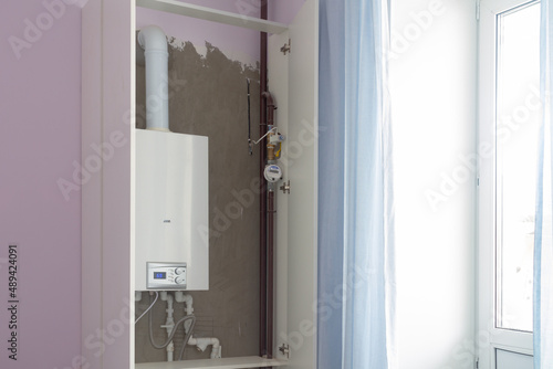 A double-circuit boiler for heating in a residential building is hidden in a white cabinet to be invisible in the interior