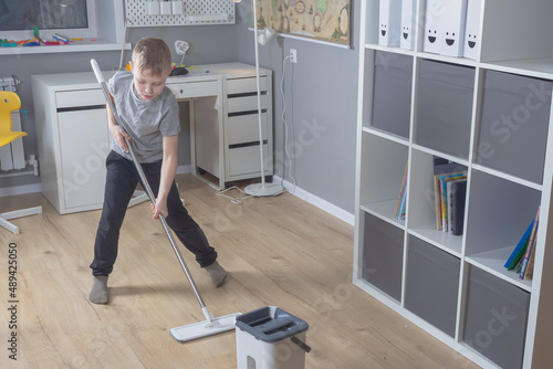 Bilde på lerret Caucasian boy mopping floors at home, child tidying up his room