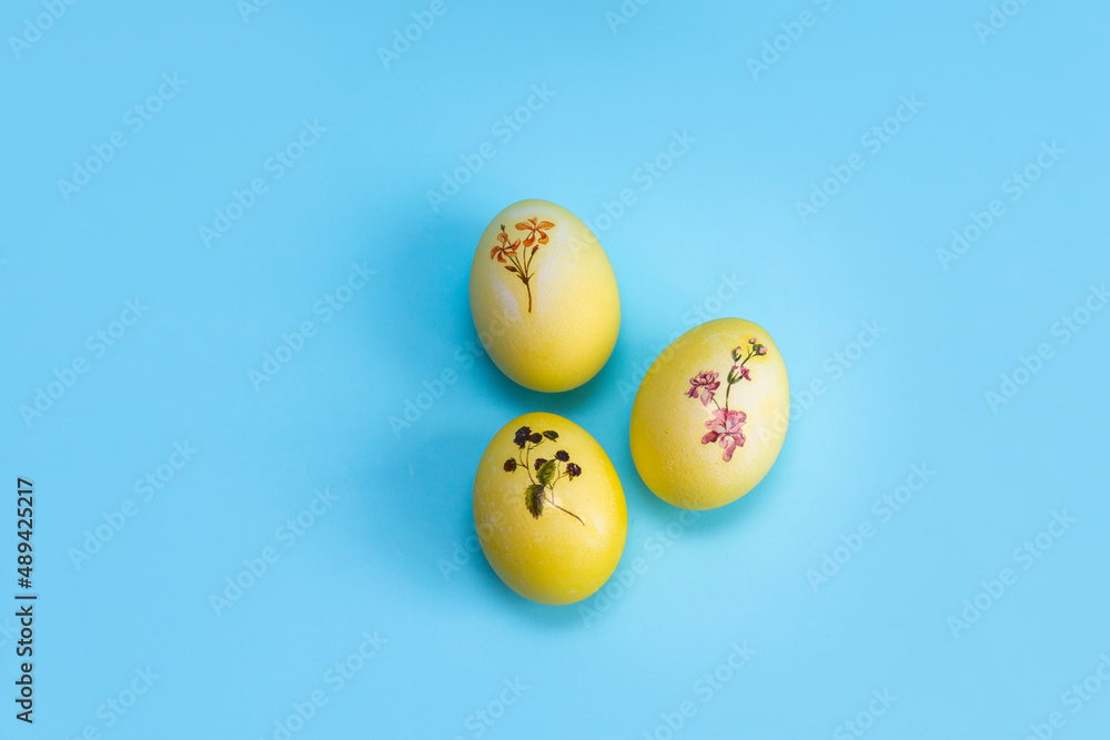 Yellow with a plant pattern of eggs lie on a bright blue background. Painted eggs for Easter