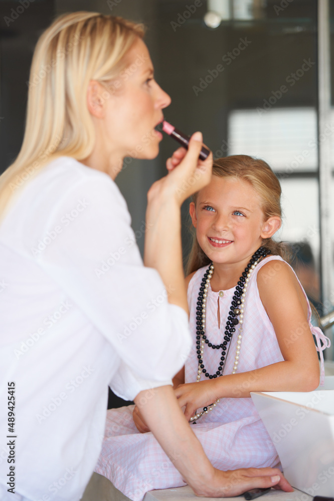 I cant wait to be a grown-up. Little girl watching her mother apply her make-up.