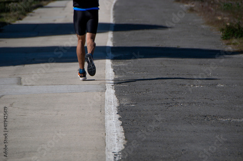 legs of man running in sportswear on asphalt road with two lanes of different color