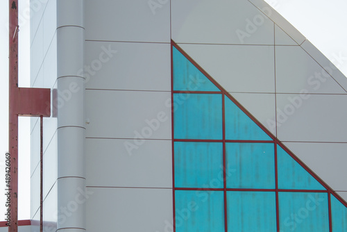 The exterior wall of a contemporary commercial style building with aluminum metal composite panels and glass windows. The futuristic building has engineered diagonal cladding steel frame panels.