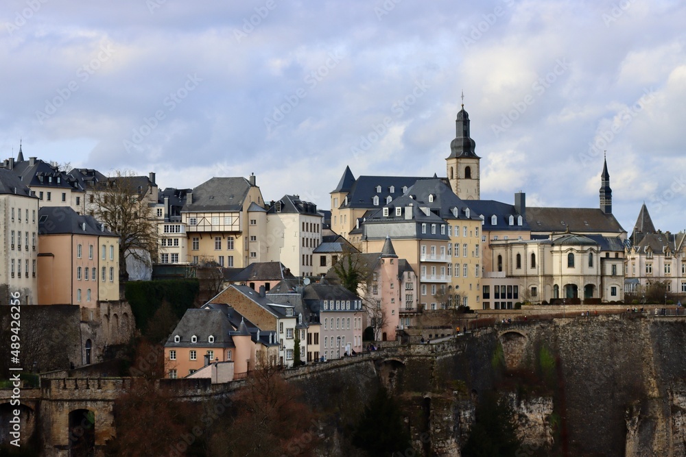 Tower of Saint Michael's Church seen over some buildings of Luxembourg old town. View over Alzette river valley on early spring day