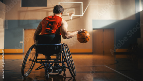 Wheelchair Basketball Player Dribbling Ball Like a Professional, Ready to Shoot and Score Goal. Determination, Motivation of a Person with Disability Excelling at Team Sport. Back View Shot © Gorodenkoff