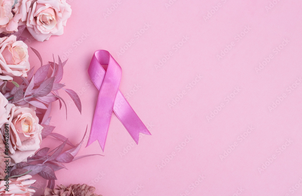 Pink ribbon and flowers on pink background with space for text. Women's day concept and breast cancer awareness Pink ribbon and flowers on pink background with space for text. Women's day concept and breast cancer awareness