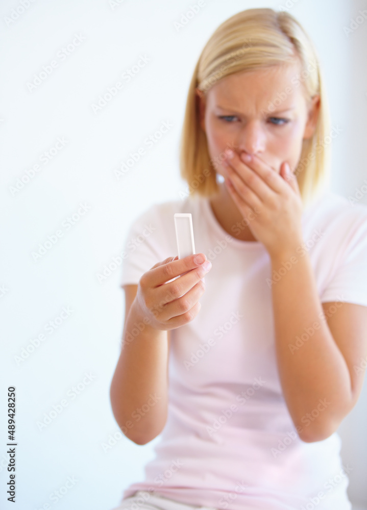 Shes undecided on the pregnancy test. A young woman looking nervous about the a pregnancy test in her hand. Shes undecided on the pregnancy test. A young woman looking nervous about the a pregnancy test in her hand.