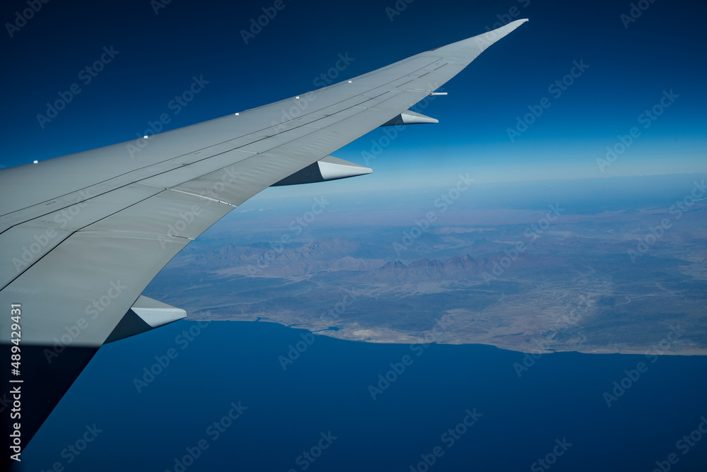 Airplane wing seen from the window, in the background the west coast of the Arabian Peninsula, Red Sea Airplane wing seen from the window, in the background the west coast of the Arabian Peninsula, Red Sea