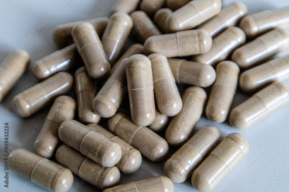 Brown capsules close-up. The scattering of capsules on a light background is close. Brown capsules close-up. The scattering of capsules on a light background is close.