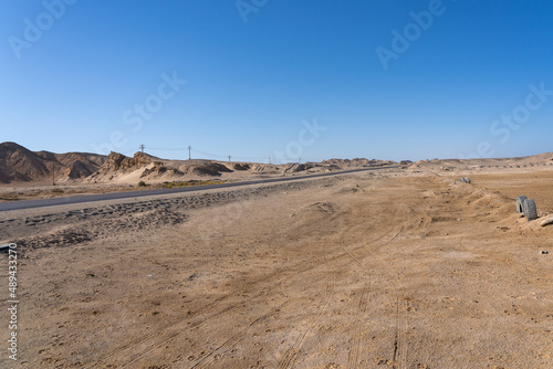 Asphalt road along sand dunes in desert