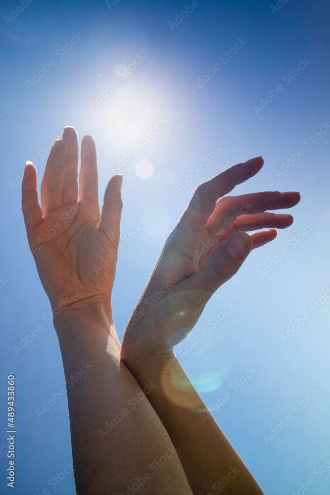 Female hands in the blue sky in the backlight Female hands in the blue sky in the backlight