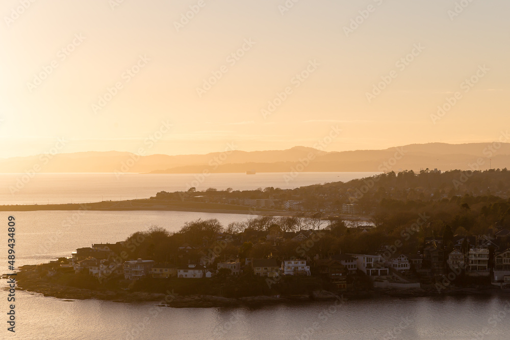 High angle north-west view of the Oak Bay residential area, with creeks in soft focus background during a hazy winter sunset from the Walbran Park Lookout, Victoria, British Columbia, Canada