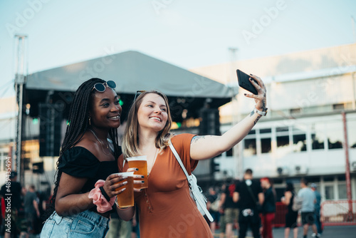 Two beautiful friends taking selfie with a smartphone on a music festival © Zamrznuti tonovi