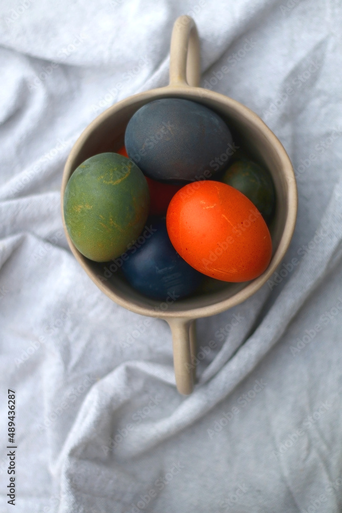 Ceramic bowl filled with painted Easter egss in jewel tones. Flat lay. Ceramic bowl filled with painted Easter egss in jewel tones. Flat lay.