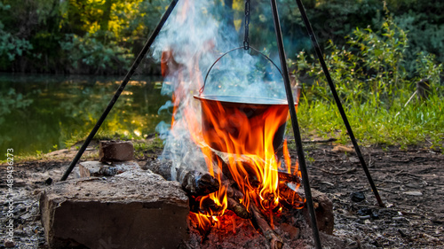 Cooking on a campfire in nature, cooking on a campfire in the campaign. Camp kitchen, cooking in the forest on a fire. Pot on an open fire. The concept of camping life.