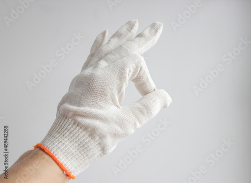 A hand in a white glove on a white background shows the "OK" sign. The concept of protection. COVID-19.