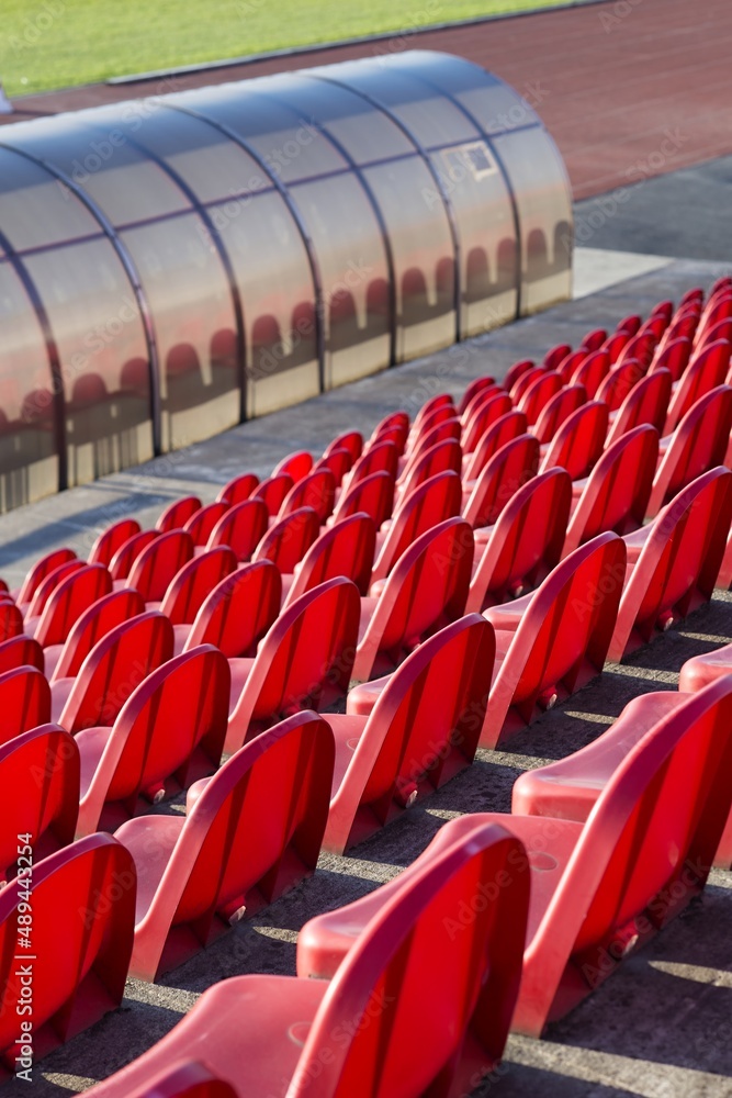 Fototapeta premium red benches of soccer - athletic stadium, sun set, place for spectators and athletes