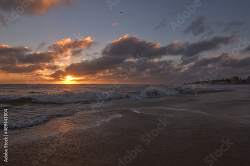 playa relajante en el atardecer con nubes y olas tranquilas espumantes photo