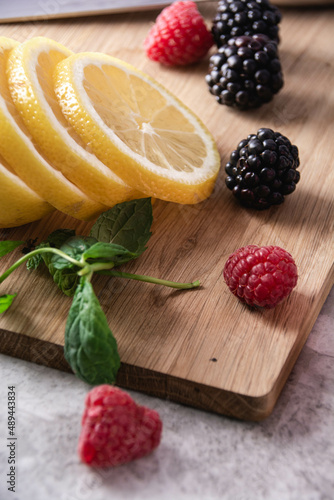 Food and Drink ingredients Lemon Mint Blackberry Rasperry on Wooden Cutting Board photo