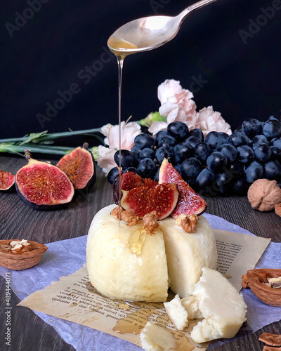 Принти на полотні Honey pouring from a spoon onto a sweet white panna cotta dessert decorated with fresh figs and walnuts