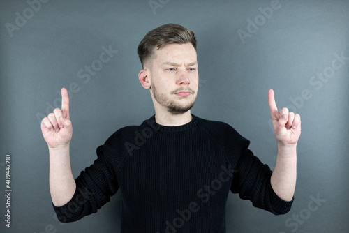 Junger Mann zeigt mit zwei Fingern nach oben Portrait