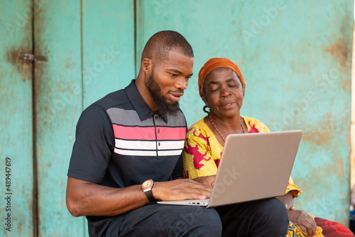 young black man using a laptop with an old woman photo