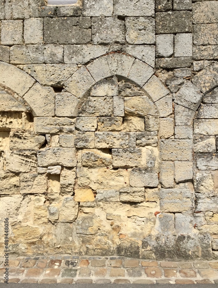 Saint Emilion, Bordeaux, France. Wall. Fragment of stone medieval wall decorated with arches. Limestone stone wall