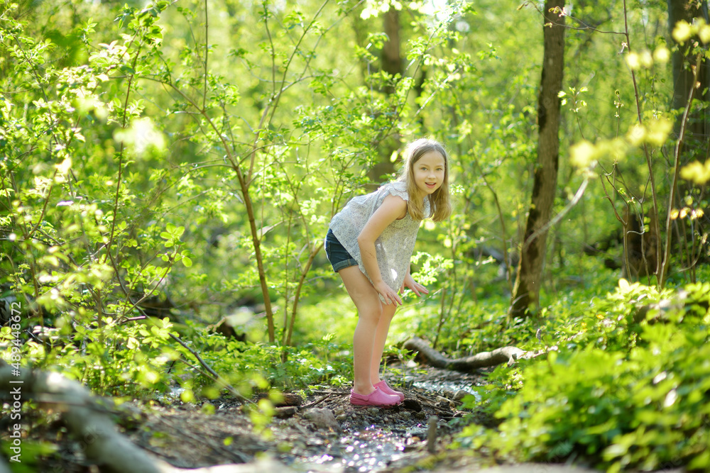 Cute young girl having fun by a river on warm spring day. Child playing by a water. Cute young girl having fun by a river on warm spring day. Child playing by a water.