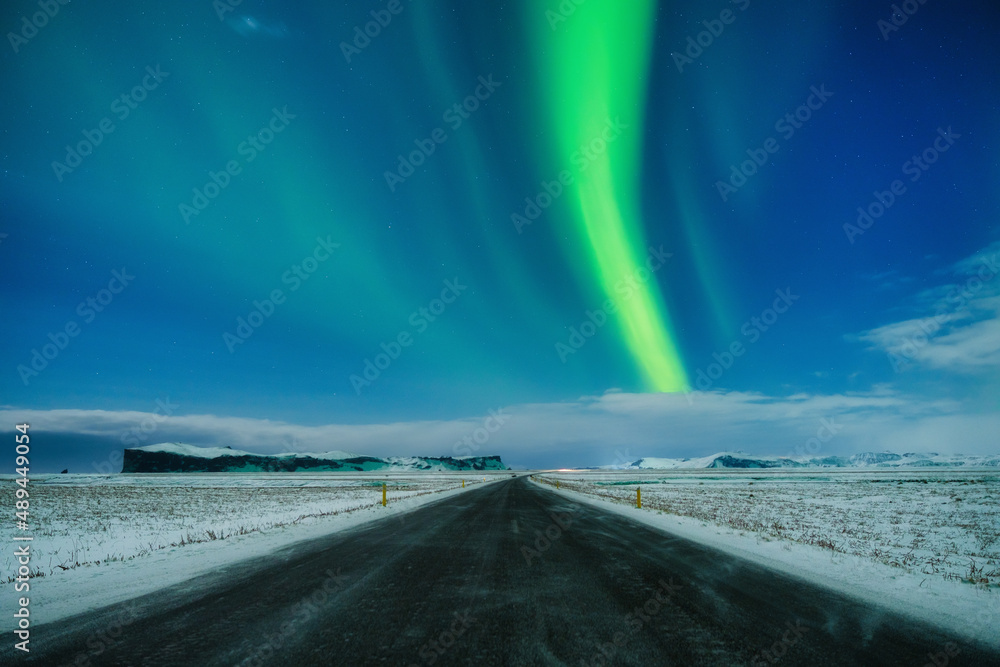 Aurora Borealis in Iceland. Northern Lights over the road. A winter night landscape with bright lights in the sky. Landscape in the north in winter time. A popular place to travel.