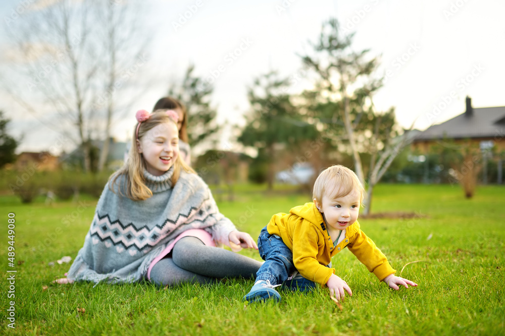 Big sister and her toddler brother having fun outdoors. Young girl playing with baby boy on spring day. Children with large age gap.