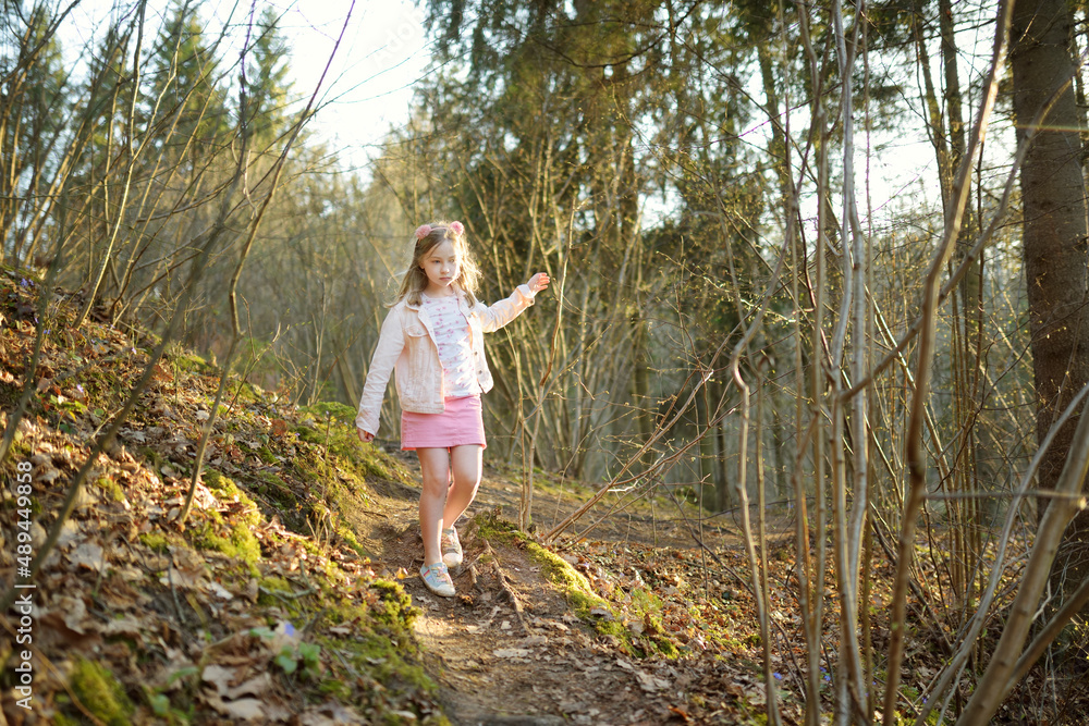 Adorable young girl having fun during a hike in the woods on beautiful sunny spring day. Active family leisure with kids. Adorable young girl having fun during a hike in the woods on beautiful sunny spring day. Active family leisure with kids.
