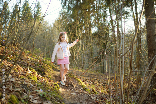 Adorable young girl having fun during a hike in the woods on beautiful sunny spring day. Active family leisure with kids. © MNStudio