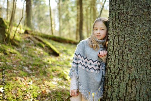 Adorable young girl having fun during a hike in the woods on beautiful sunny spring day. Active family leisure with kids.
