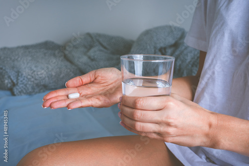 Woman holding glass of still water and taking painkiller from headache pain. Woman taking pills or antidepressant