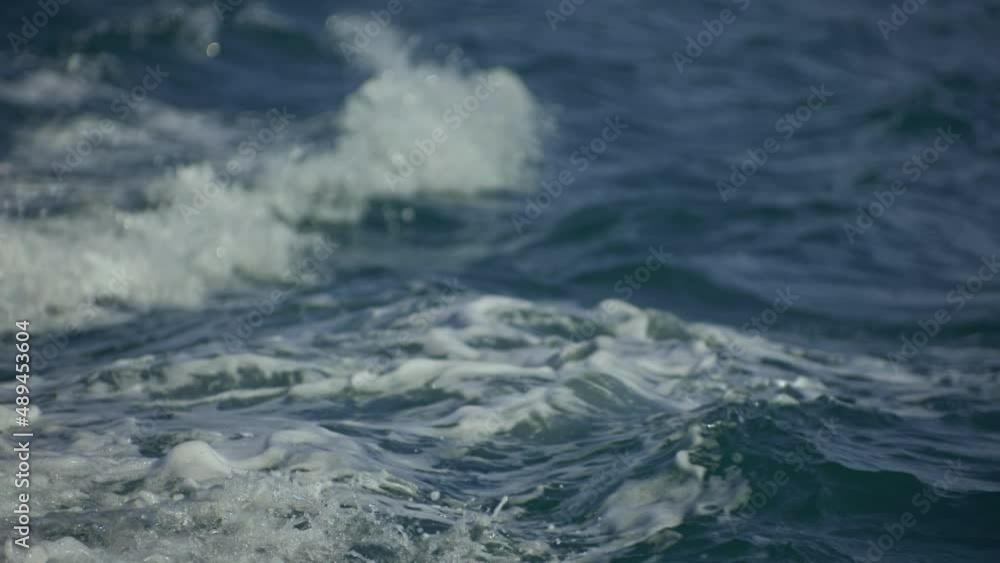 View of the blue sea water side from the stern of the ship, waves with foam and splashes, disperse after the movement of the ship. Close-up, slow motion 180 fps View of the blue sea water side from the stern of the ship, waves with foam and splashes, disperse after the movement of the ship. Close-up, slow motion 180 fps