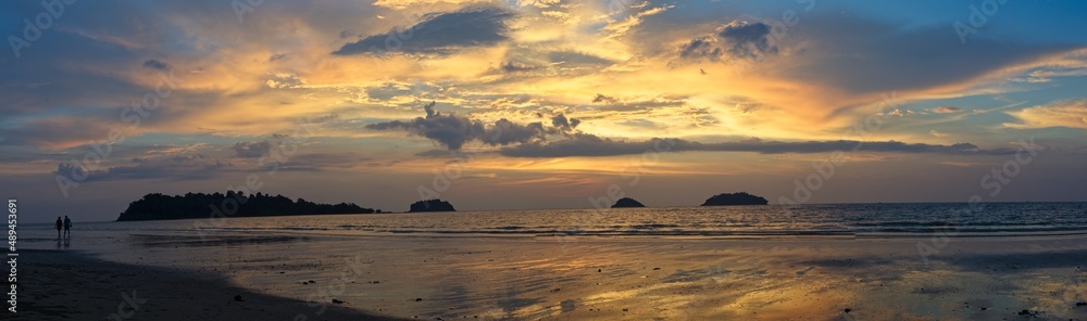 Panorama of spectacular sunset on deserted beach with bright colors and no people with palm trees on Koh Chang Island, Thailand.