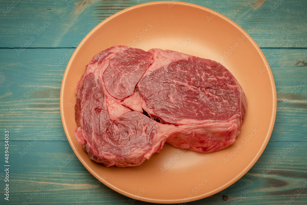Food photography, meat. Beef steak on a beige plate on a turquoise aged background.