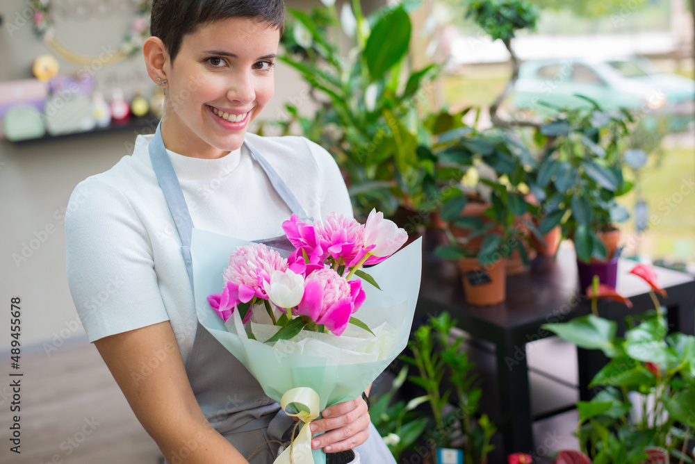 Young woman professional florist working with flowers in her flower shop.