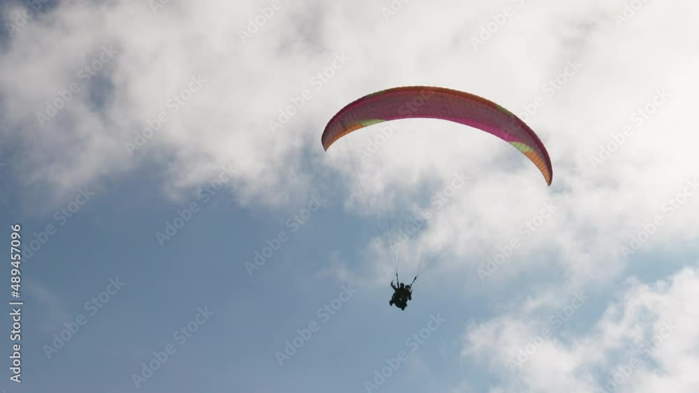 People try paragliding flying with parachutes against clouds People try paragliding flying with parachutes against clouds